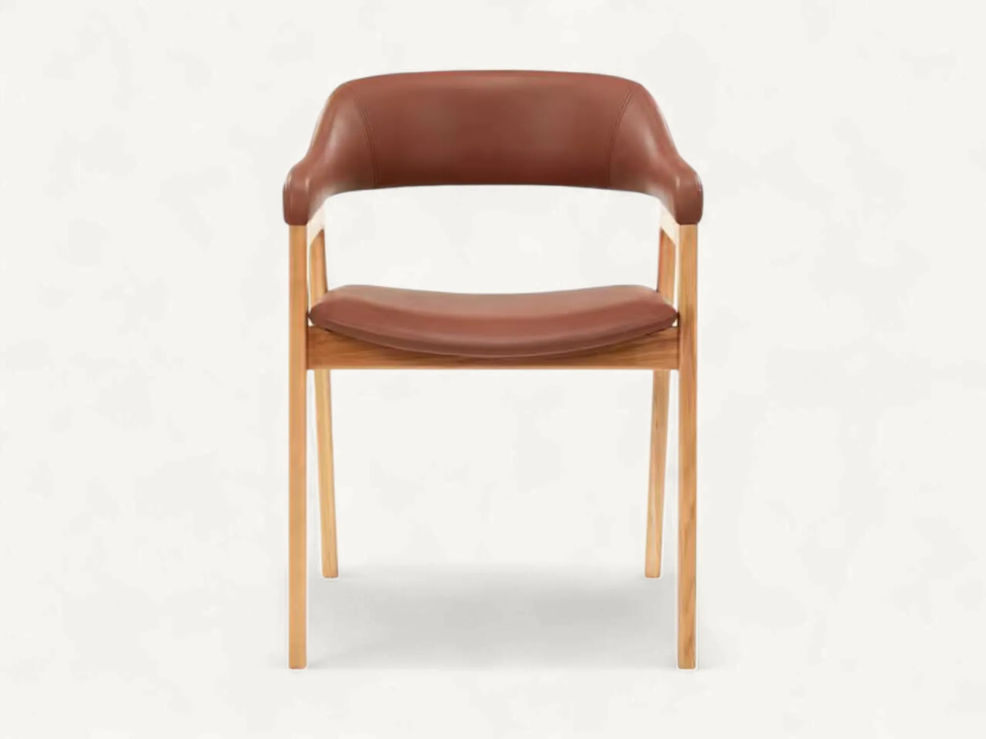 Mid-Century teak wood dining chair with curved brown leather upholstered seat and tapered legs.