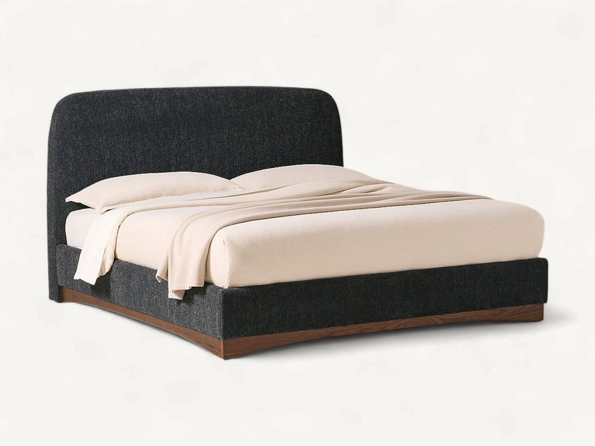Low-profile upholstered platform bed in textured charcoal gray fabric, featuring a rounded rectangular headboard and a warm brown wooden plinth base with a subtle arched bottom edge.