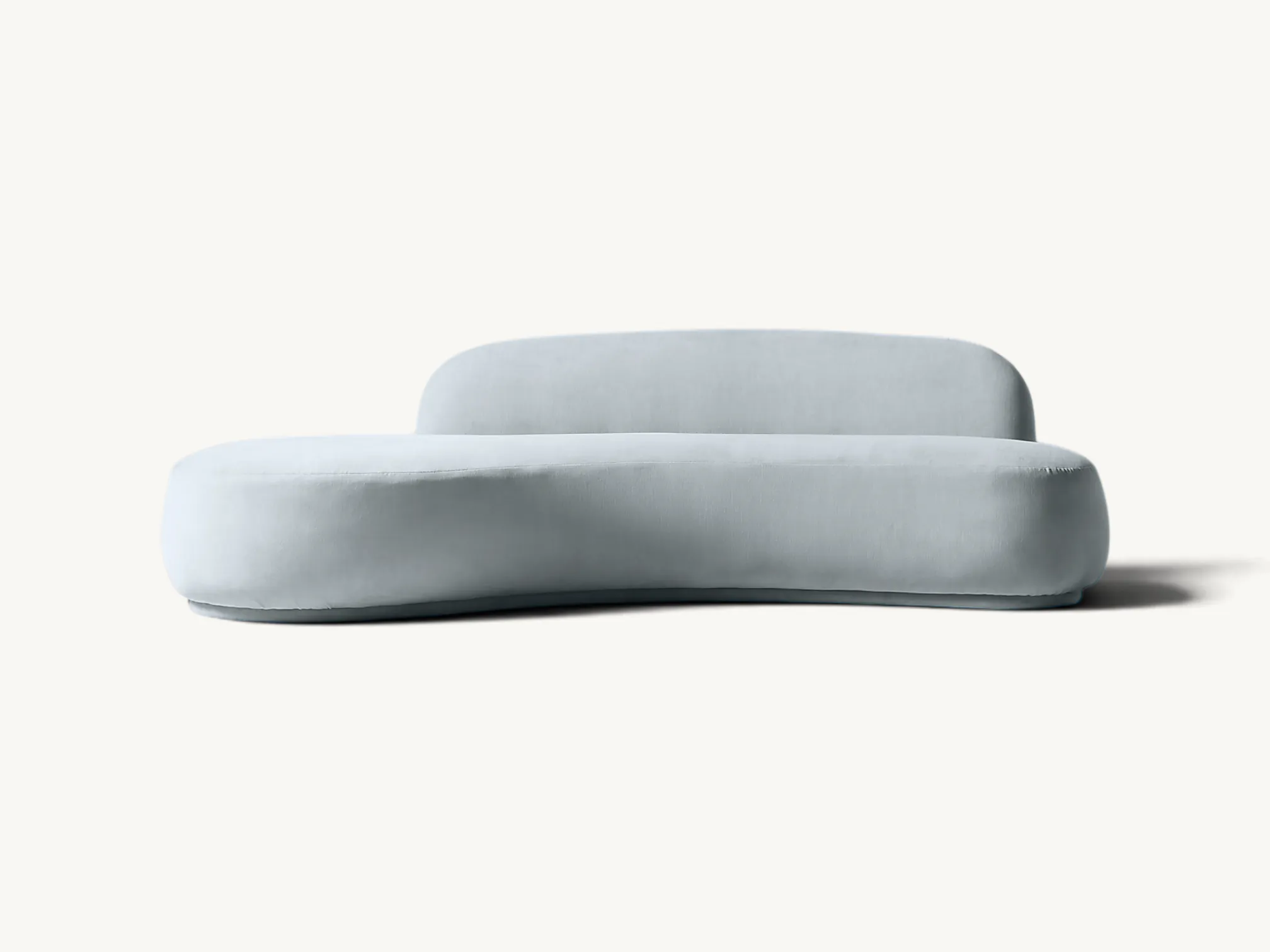 Upholstered curved kidney-shaped sofa in soft light blue velvet featuring an asymmetrical low backrest