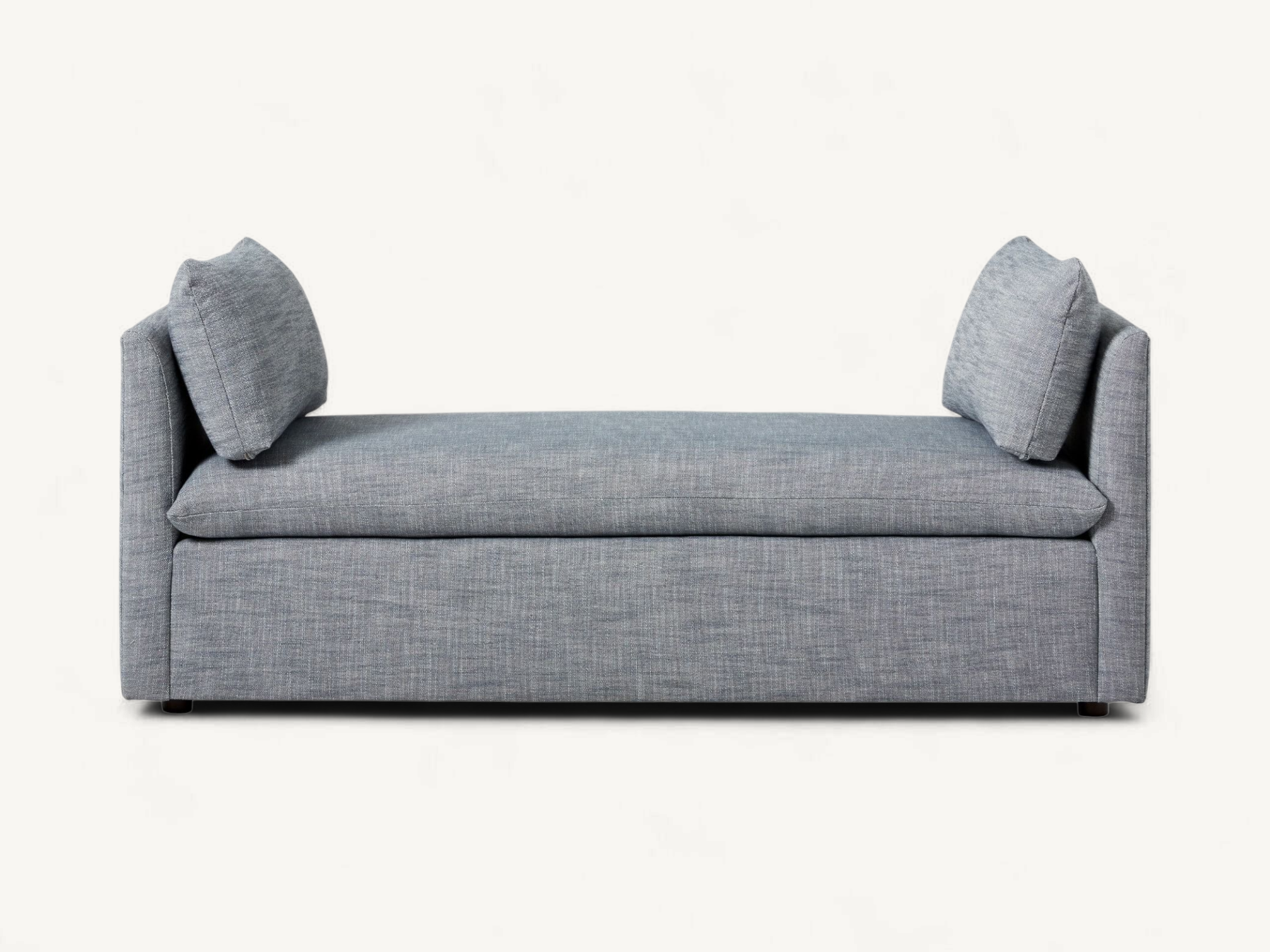 Modern upholstered bench in grey fabric with low side armrests and two rectangular accent pillows.
