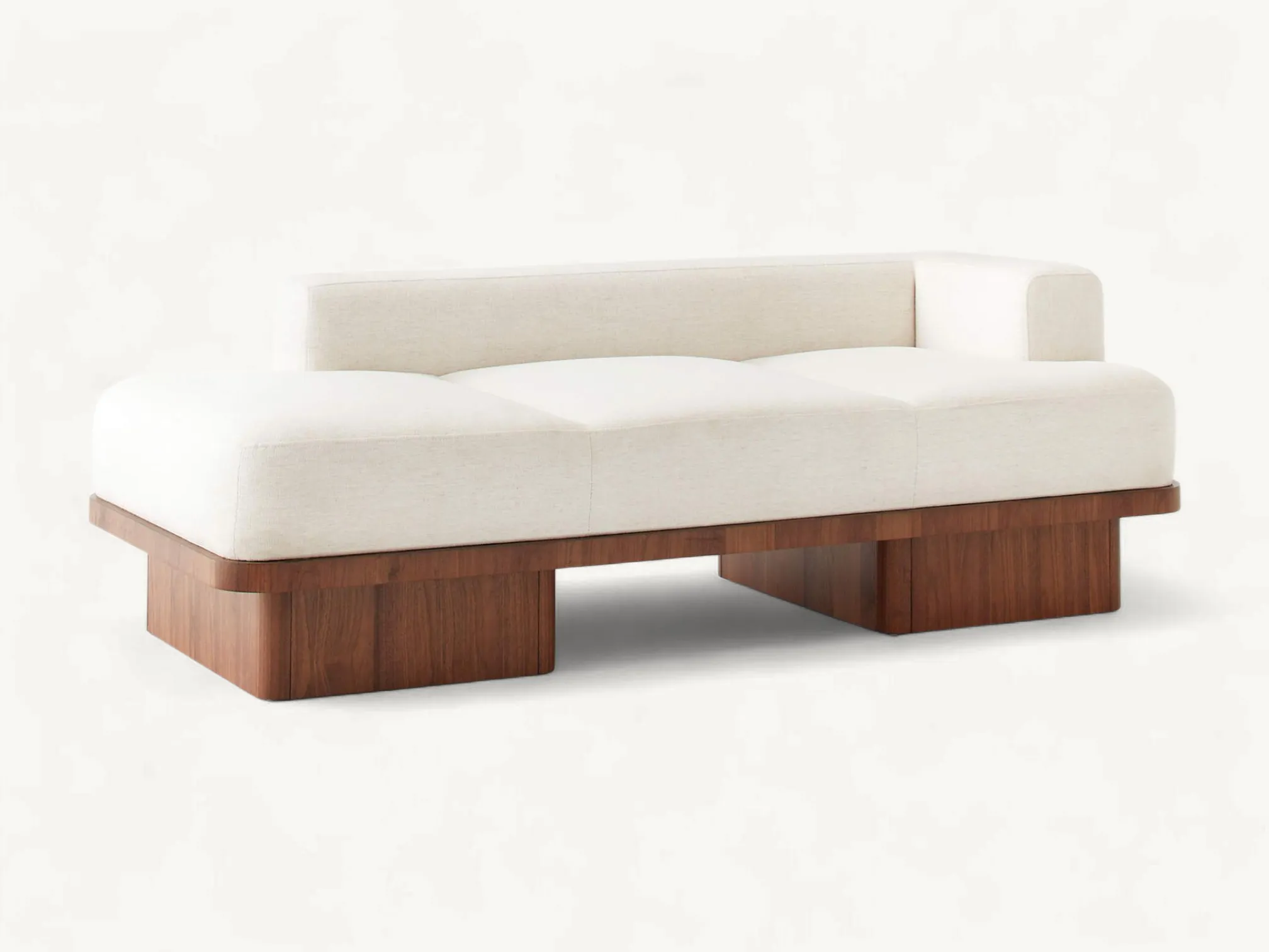 Asymmetrical cream fabric sofa with a thick solid teak wood base and rounded architectural legs.