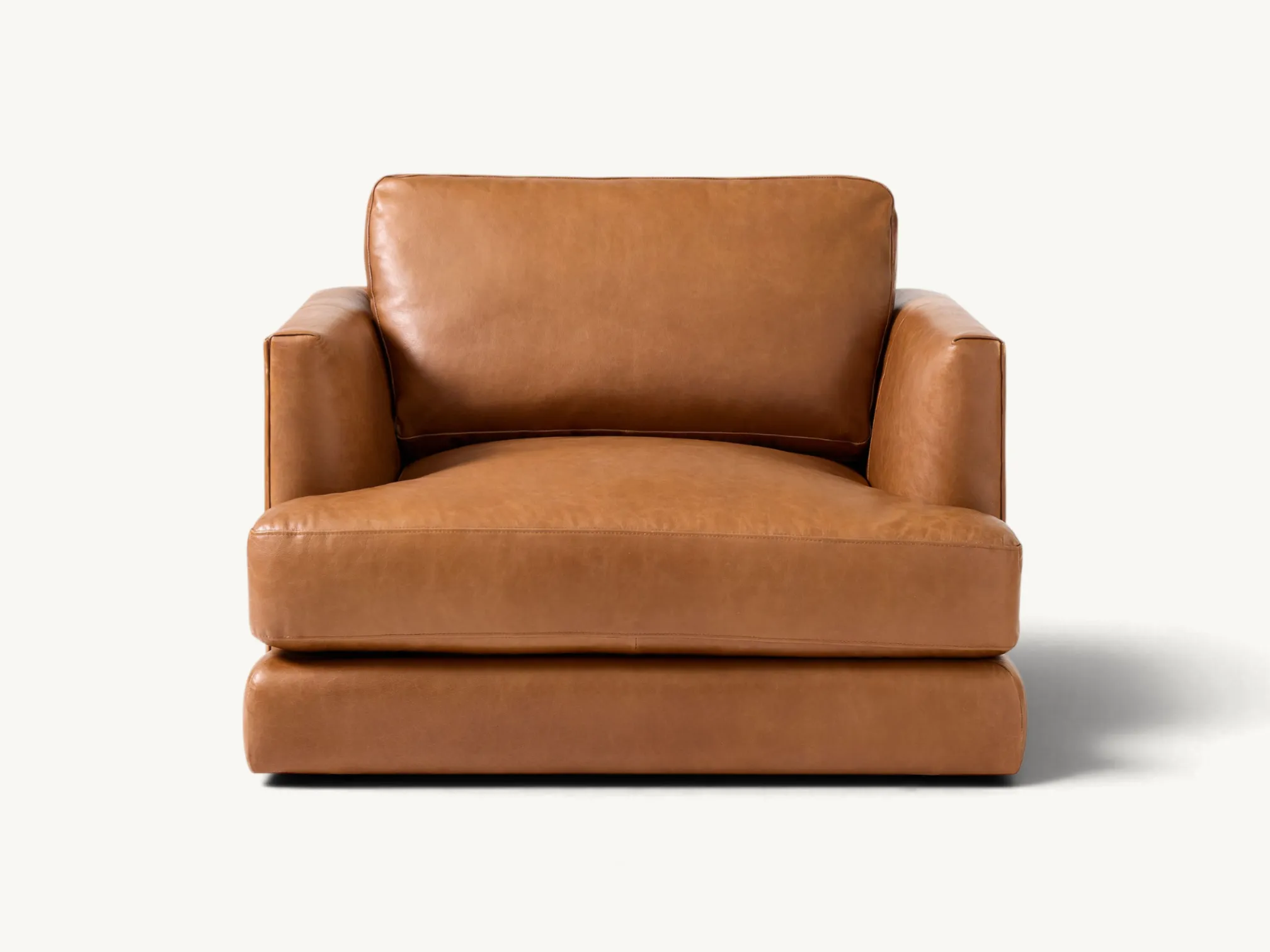 Cognac tan leather oversized armchair with deep seating and wide armrests set in a modern living room