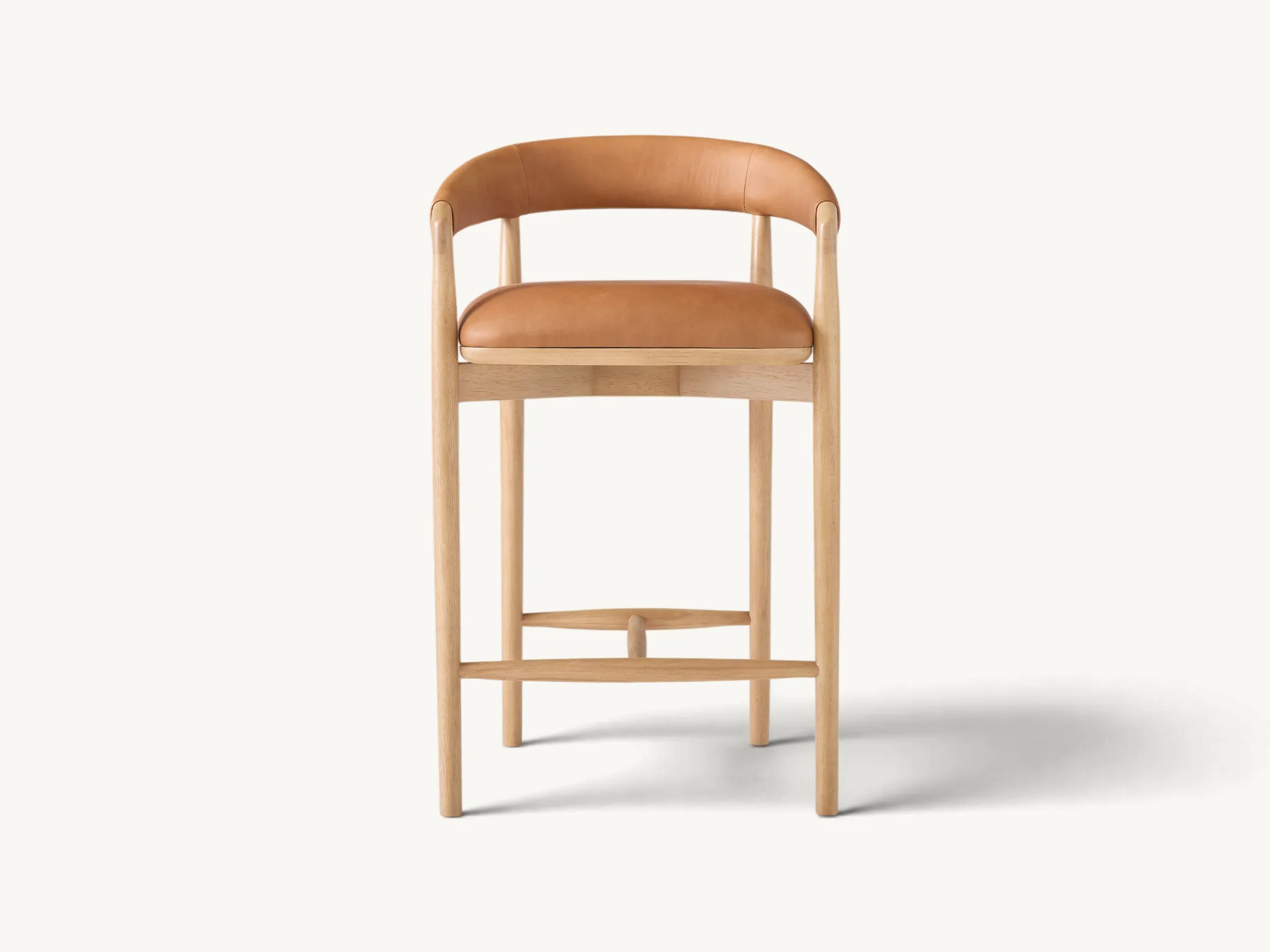 Wooden counter stool with curved leather backrest and tan seat cushion in natural light wood finish
