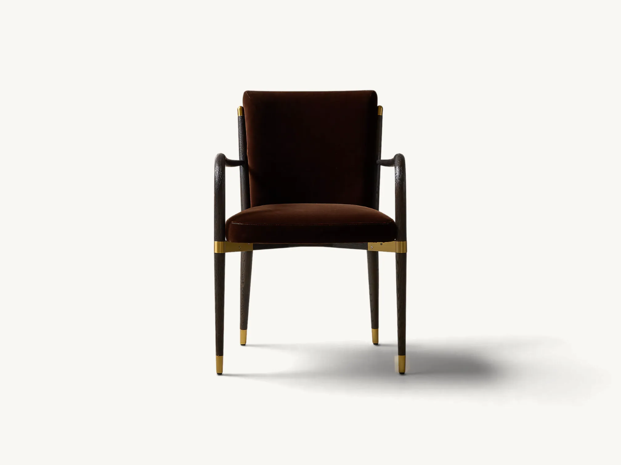 Upholstered dining armchair in dark brown velvet with curved wooden armrests and brass metal accents