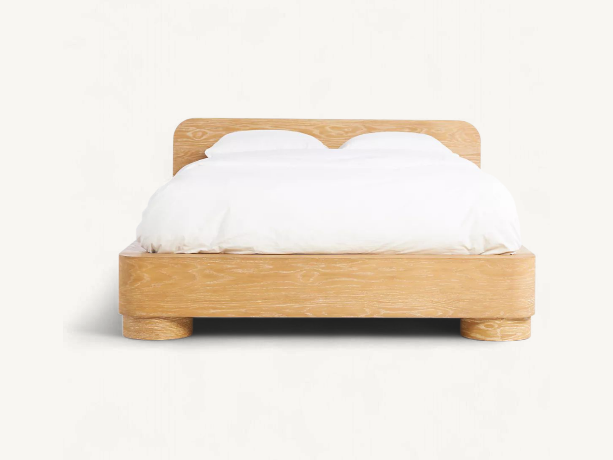Minimalist solid teak wood bed frame with rounded corners, natural grain finish, and thick cylindrical platform legs.
