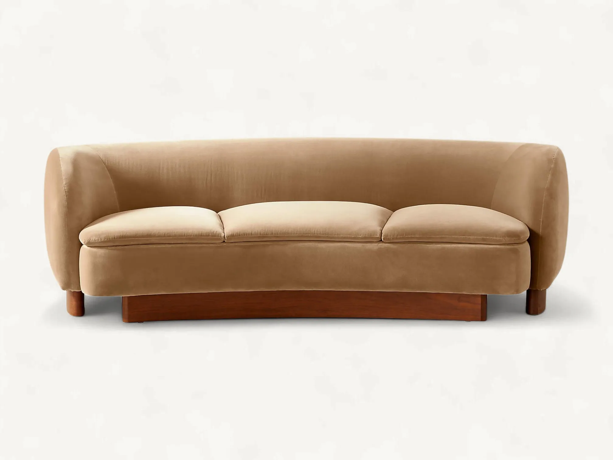 Curved velvet three-seater sofa featuring a wrap-around backrest and a solid teak wood plinth base in a mid-century modern style.