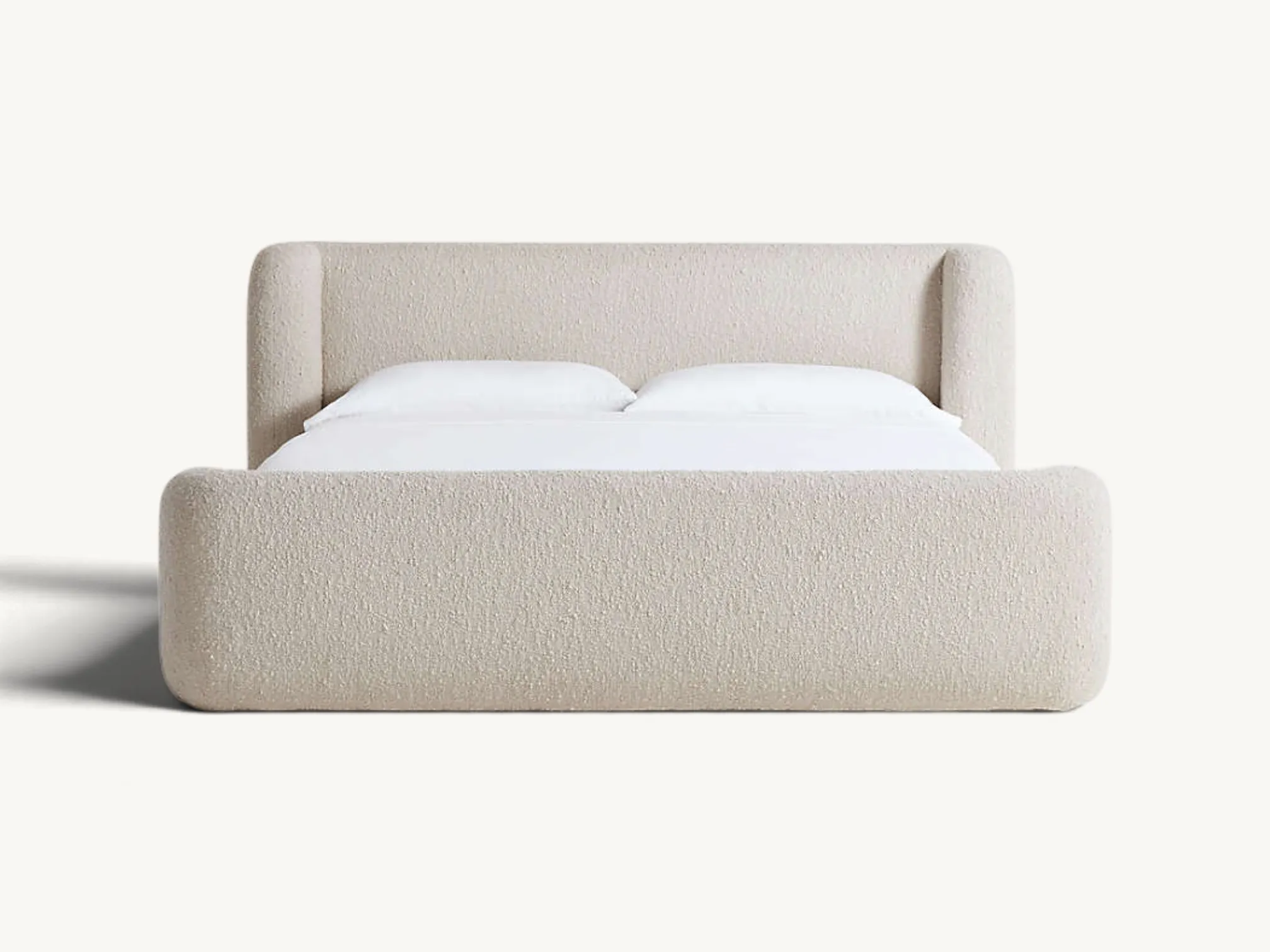 Low-profile upholstered platform bed frame in cream bouclé fabric with rounded sides and a cushioned headboard
