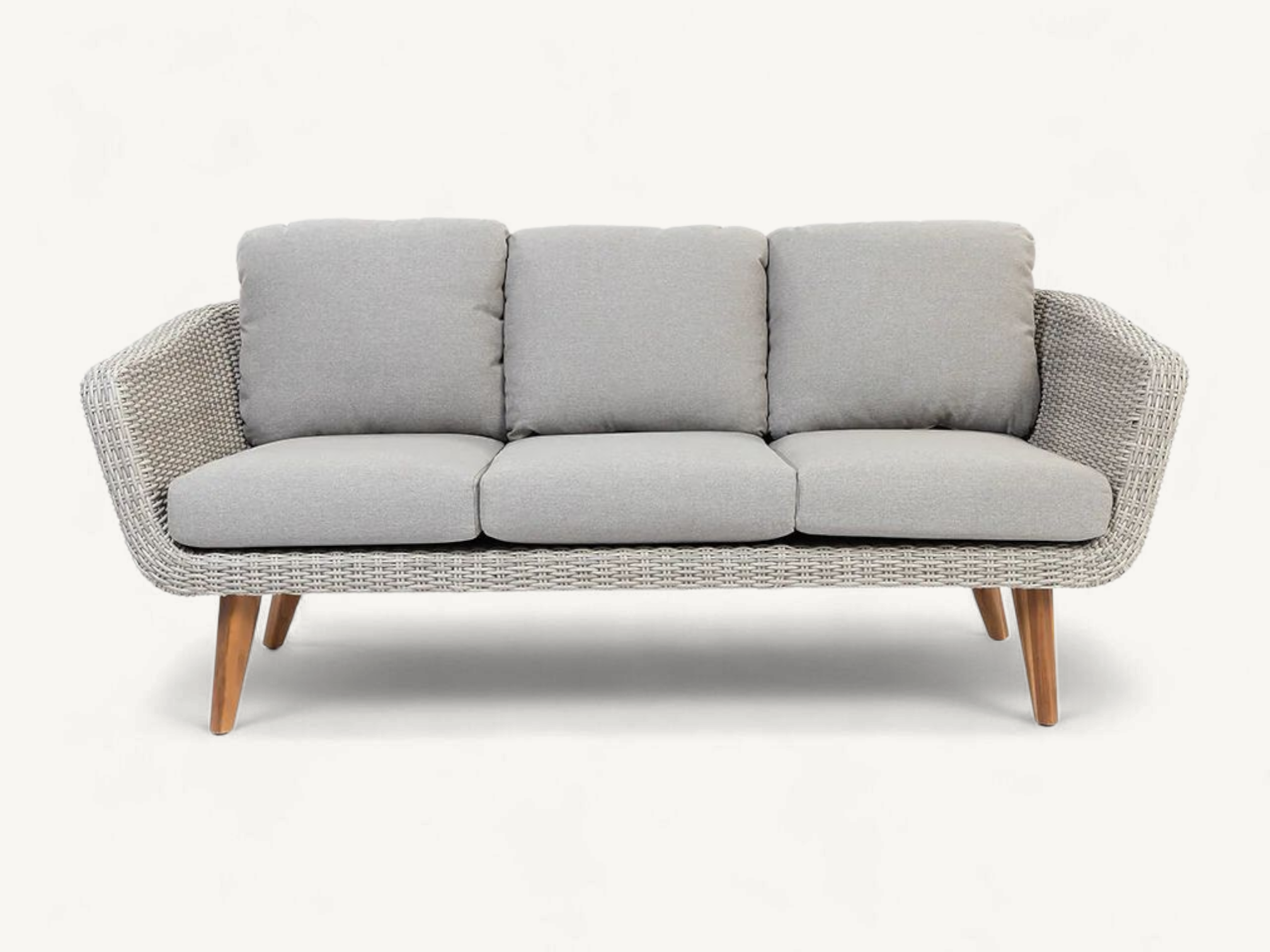 Organic curved outdoor sofa made of full natural rattan with plush cream cushions.
