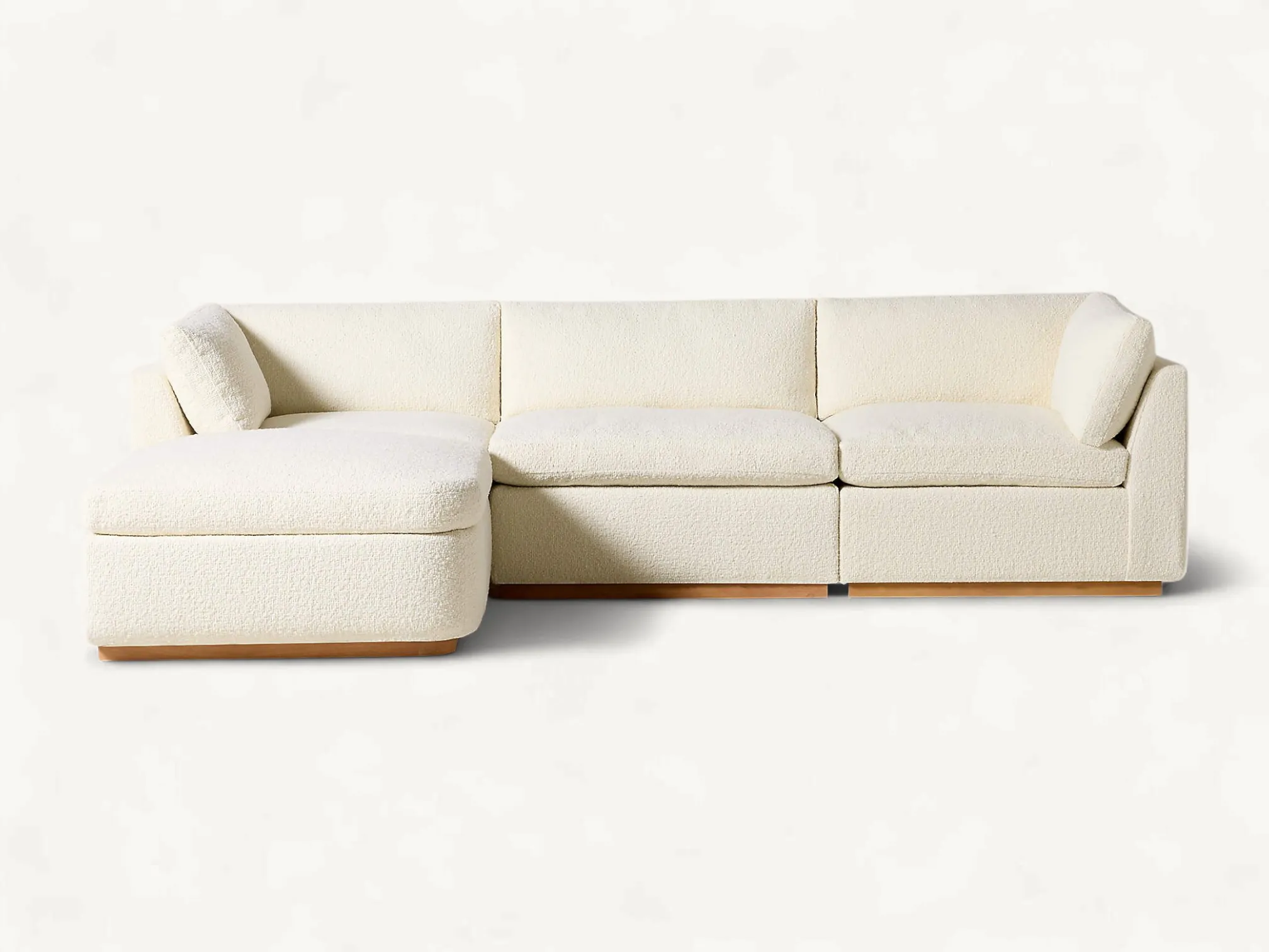 Modern four-piece modular sectional sofa with an integrated chaise lounge, ivory textured upholstery, and a low-profile solid teak wood base.