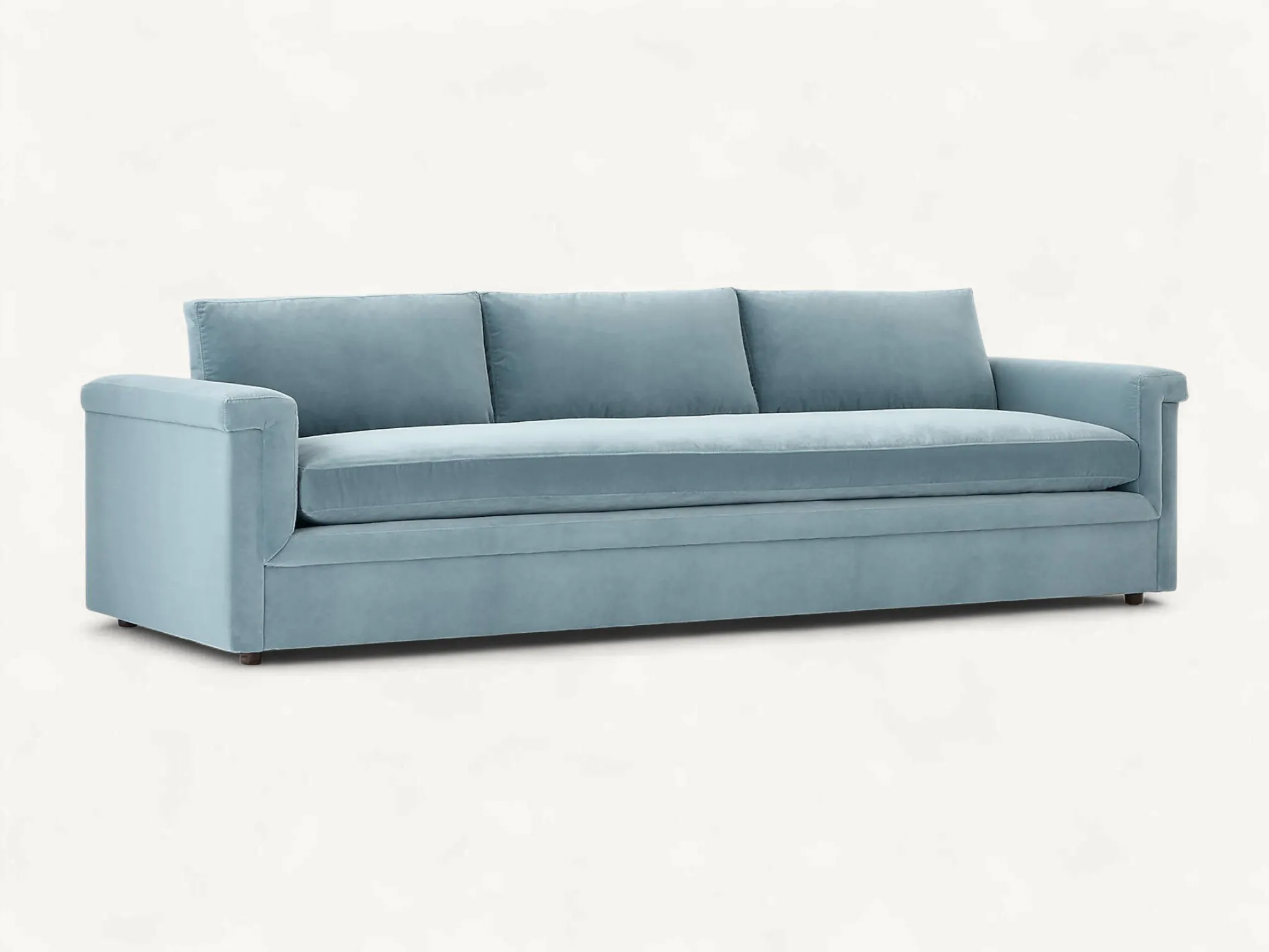Modern low-profile teak wood sofa with light blue velvet upholstery and long bench seat cushion.