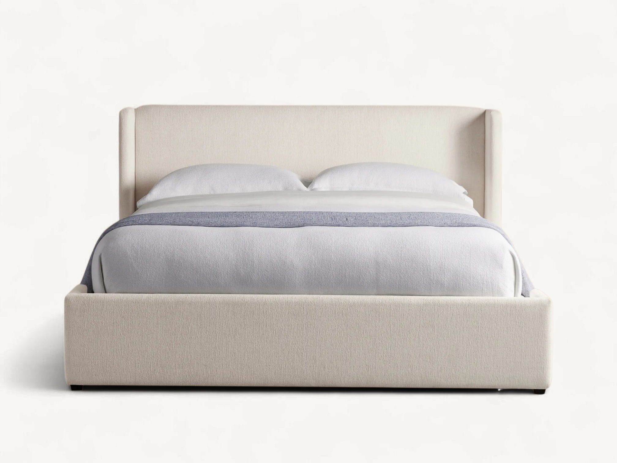 Modern fully upholstered teak wood bed frame with cream textured fabric and wingback headboard.